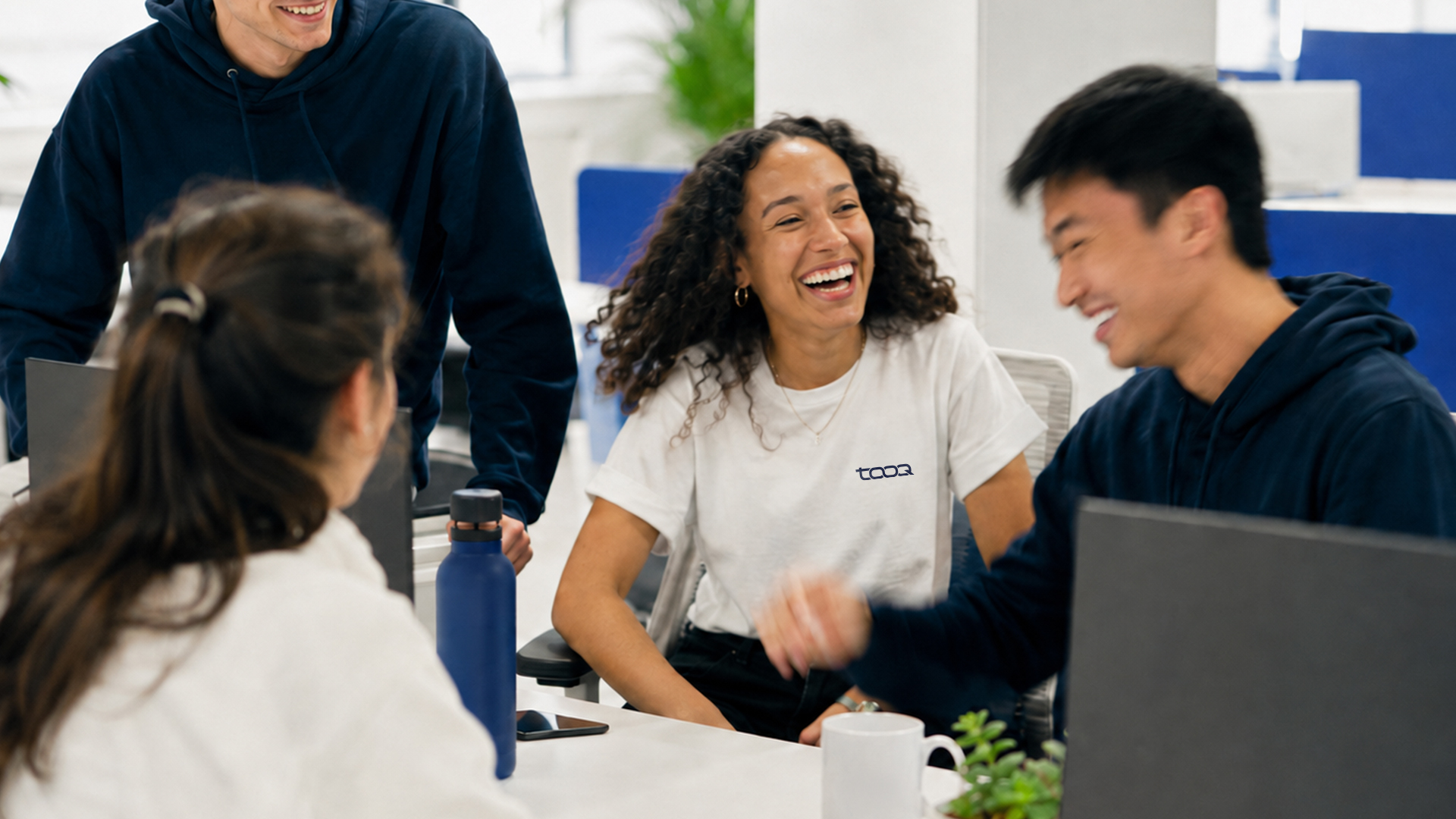 People collaborating in a bright workspace, with Tooq apparel.